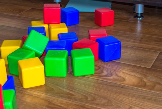 Colorful plastic cubes for children's games are scattered on the wooden floor.