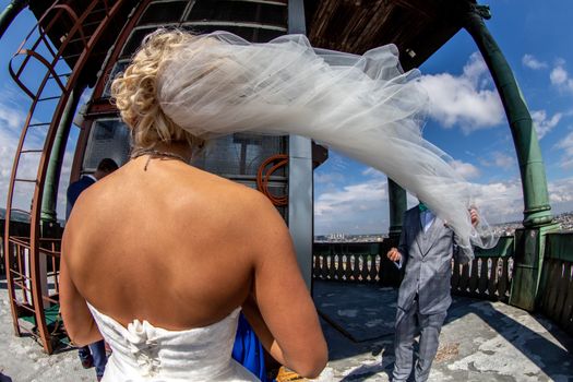 Bride and groom in st. Peter's church in Riga, Latvia. Panoramic view of Riga with cloudy blue sky. Fisheye lens.
