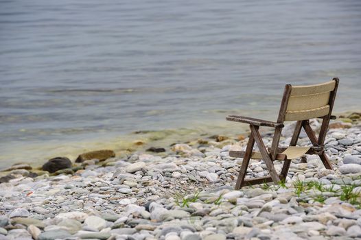 old tired wooden foldable chair at stone beach
