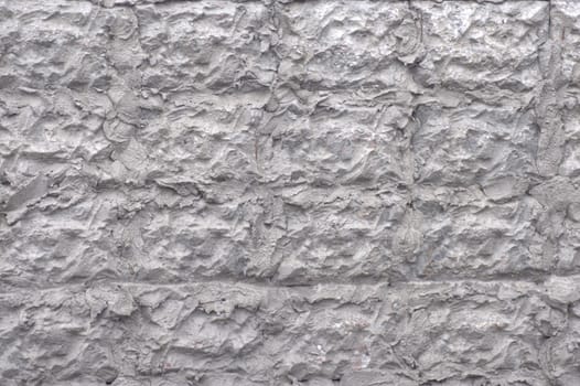 The wall of the building is decorated with a decor of cement. A close-up shot on the street.