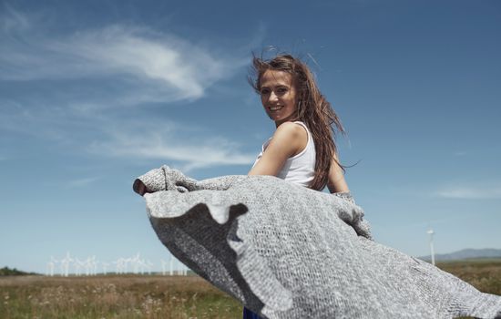 Woman with long tousled hair next to the wind turbine with the wind blowing