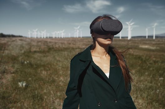 Woman wearing VR headset at the field next to the wind turbines