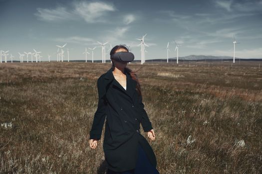 Woman wearing VR headset at the field next to the wind turbines