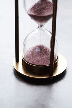 Vintage hourglass with flowing sand on dark background