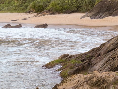 Deserted beach, with waves breaking hard on the rocks, forming foam