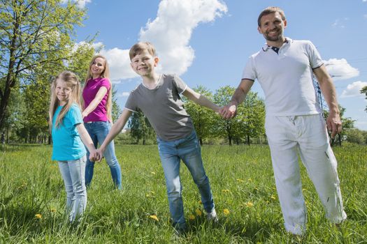 Happy young family of couple and two children spending time in summer park