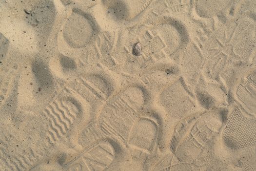 Sand on the beach with footprints and shoes. Many footprints with shoes and without shoes.