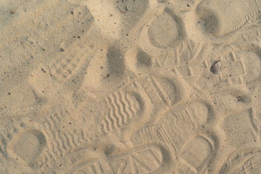 Sand on the beach with footprints and shoes. Many footprints with shoes and without shoes.