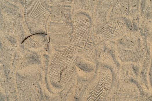 Sand on the beach with footprints and shoes. Many footprints with shoes and without shoes.