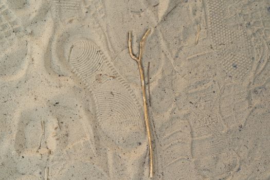 Sand on the beach with footprints and shoes. Many footprints with shoes and without shoes.