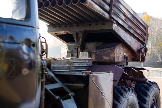 Camouflage military truck with rocket launcher. Outdoor military vehicles museum. Armor is damaged at the battlefield.