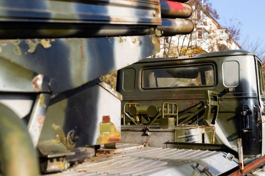 Camouflage military truck with rocket launcher. Outdoor military vehicles museum. Armor is damaged at the battlefield. Missile firing system on military armored truck close up view. Rocket launcher.