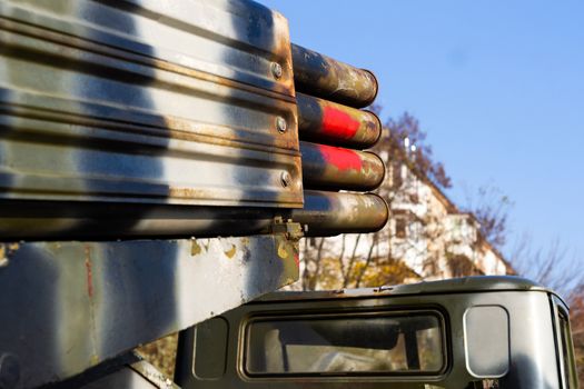 Camouflage military truck with rocket launcher. Outdoor military vehicles museum. Armor is damaged at the battlefield. Missile firing system on military armored truck close up view. Rocket launcher.