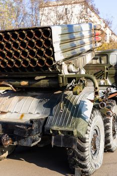 Camouflage military truck with rocket launcher. Outdoor military vehicles museum. Armor is damaged at the battlefield. Missile firing system on military armored truck close up view. Rocket launcher.