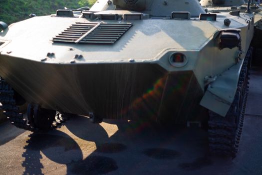 Parts of the hull of the armored infantry vehicle. In front and back of vehicle stays many different armored military vehicles. Military equipment outdoor open air museum.