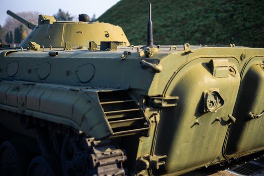 Parts of the hull of the armored infantry vehicle. In front and back of vehicle stays many different armored military vehicles. Military equipment outdoor open air museum.