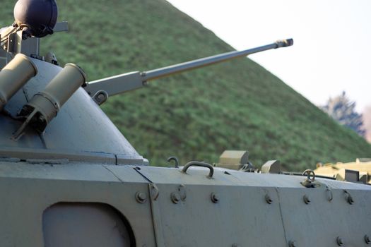 Parts of the hull of the armored infantry vehicle. In front and back of vehicle stays many different armored military vehicles. Military equipment outdoor open air museum.