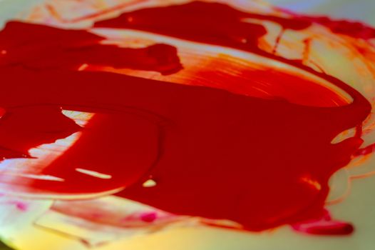 Hue red acrylic paint on glare table. Palette on table. Artist life.