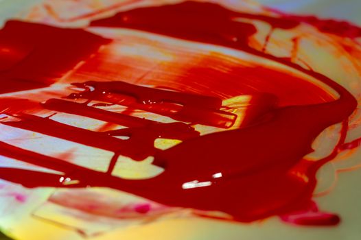 Hue red acrylic paint on glare table. Palette on table. Artist life.