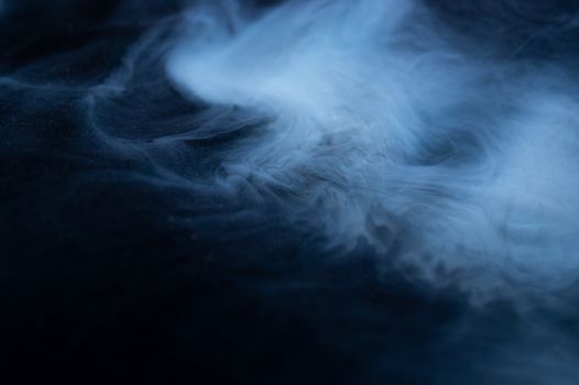 White smoke on black fabric background. Smoke spreads over the background. Vaping culture, life without cigarettes. Conceptual image.