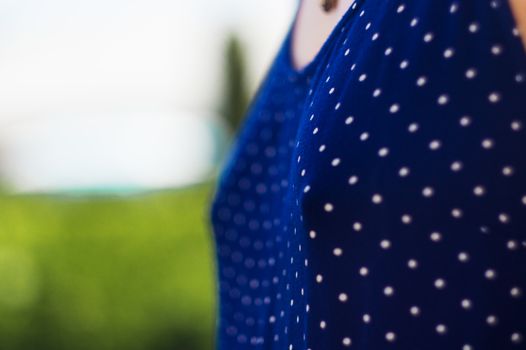 The top of the blue dress in polka dots, at the level of the female breast.