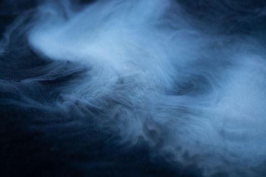 White smoke on black fabric background. Smoke spreads over the background. Vaping culture, life without cigarettes. Conceptual image.