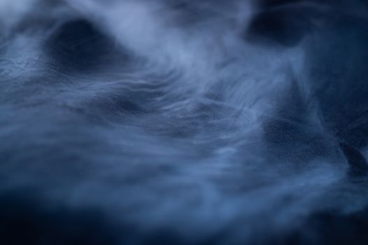 White smoke on black fabric background. Smoke spreads over the background. Vaping culture, life without cigarettes. Conceptual image.