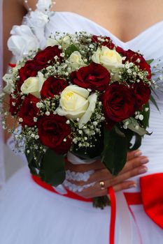 Bouquet of roses in bride hands. Weddind details in closeup view. Solemn event.