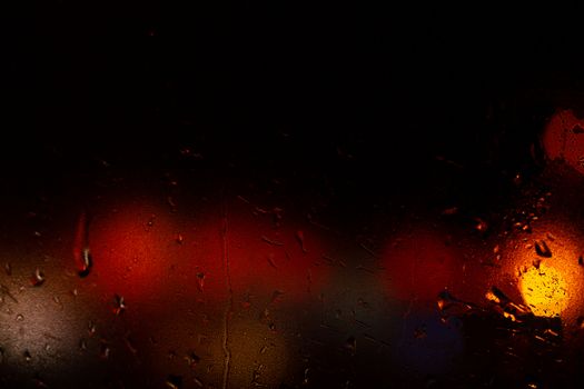 Night colorful big city lights through car windshield.

Light are defocused and blurred. Focus on windshield. Underexposed photo.