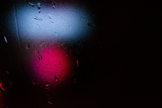 Night colorful big city lights through car windshield.

Light are defocused and blurred. Focus on windshield. Underexposed photo.