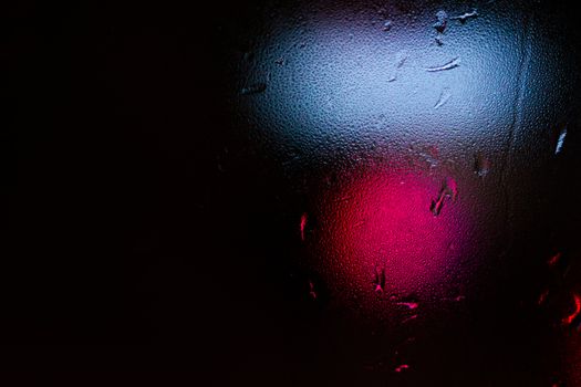 Night colorful big city lights through car windshield.

Light are defocused and blurred. Focus on windshield. Underexposed photo.