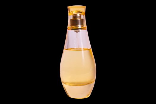 Warm yellow colour glass parfum bottle isolater on black background.