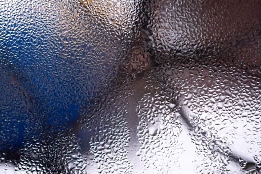 Water drops on glass window close up with blurred background. Drops in macro. Condensate on window closeup. Wet air.