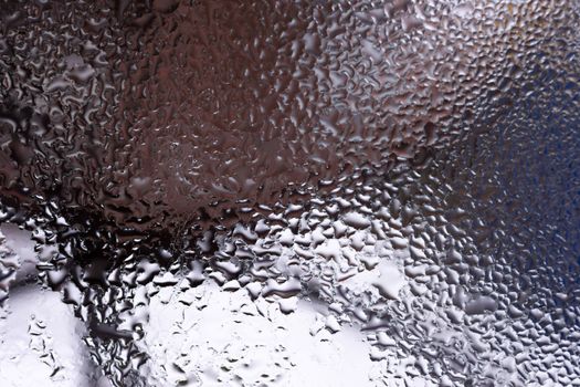 Water drops on glass window close up with blurred background. Drops in macro. Condensate on window closeup. Wet air.