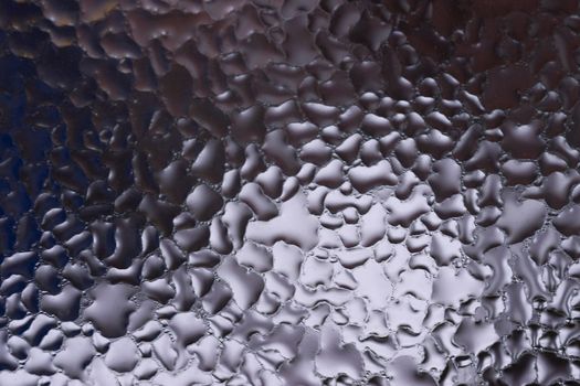Water drops on glass window close up with blurred background. Drops in macro. Condensate on window closeup. Wet air.