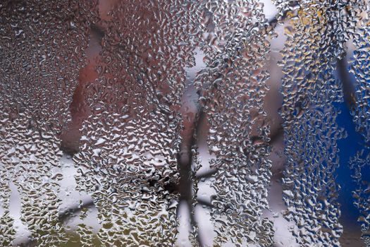 Water drops on glass window close up with blurred background. Drops in macro. Condensate on window closeup. Wet air.