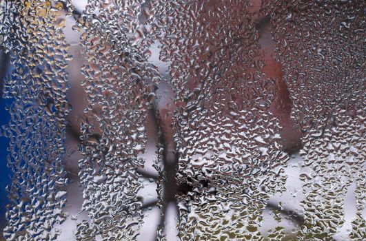 Water drops on glass window close up with blurred background. Drops in macro. Condensate on window closeup. Wet air.