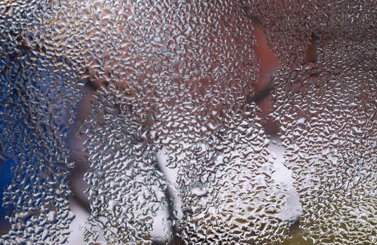 Water drops on glass window close up with blurred background. Drops in macro. Condensate on window closeup. Wet air.