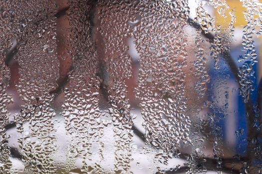 Water drops on glass window close up with blurred background. Drops in macro. Condensate on window closeup. Wet air.