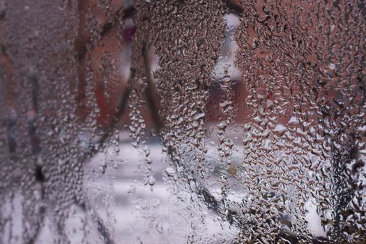 Water drops on glass window close up with blurred background. Drops in macro. Condensate on window closeup. Wet air.