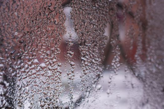 Water drops on glass window close up with blurred background. Drops in macro. Condensate on window closeup. Wet air.
