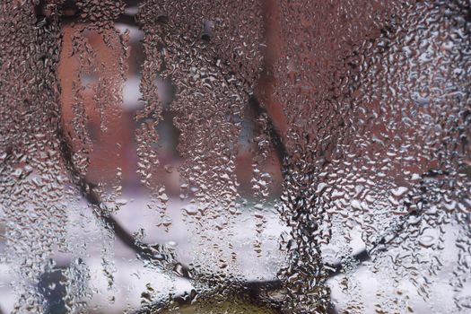 Water drops on glass window close up with blurred background. Drops in macro. Condensate on window closeup. Wet air.