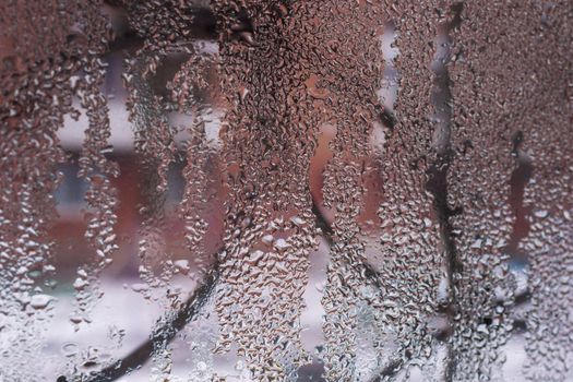 Water drops on glass window close up with blurred background. Drops in macro. Condensate on window closeup. Wet air.
