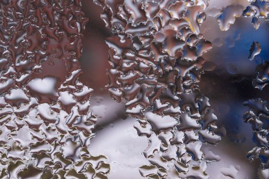 Water drops on glass window close up with blurred background. Drops in macro. Condensate on window closeup. Wet air.
