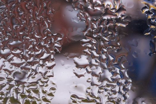 Water drops on glass window close up with blurred background. Drops in macro. Condensate on window closeup. Wet air.