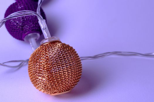 Battery garland with metallic grid balls on white background. Closeup view with blurred background.