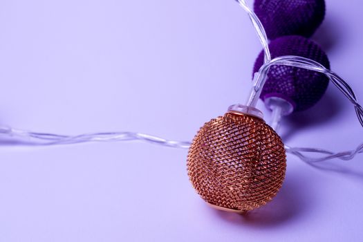 Battery garland with metallic grid balls on white background. Closeup view with blurred background.