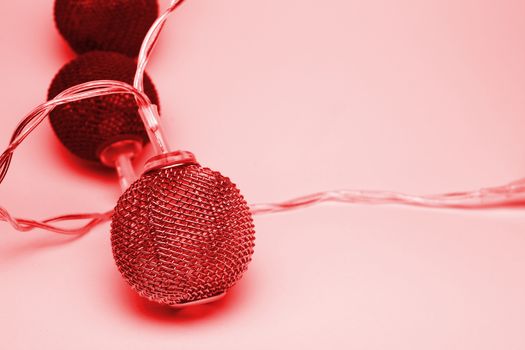 Battery garland with metallic grid balls on white background with soft red toning Closeup view with blurred background.
