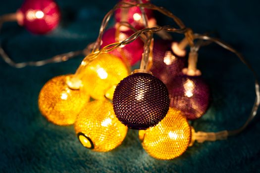 Battery garland with metallic grid balls on blue blanket. Closeup view with blurred background.