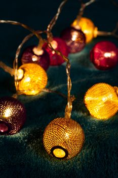 Battery garland with metallic grid balls on blue blanket. Closeup view with blurred background.